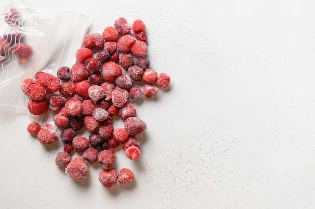 Frozen strawberries in plastic packet on white view from above