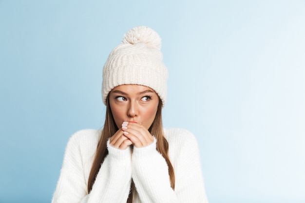 Frozen young woman wearing hat and sweater standing