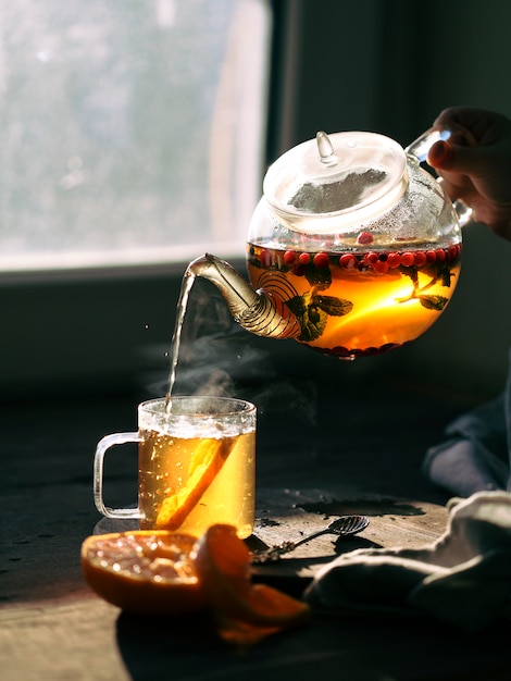 Fruit and berry tea in a transparent teapot and mug