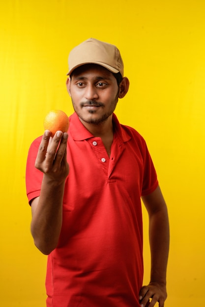 Fruit delivery concept : Indian delivery man holding orange fruit in hand