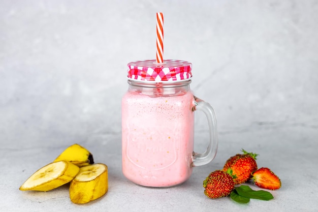 Fruit drink in glass jars with fresh strawberries and bananas Healthy summer drink for a vegan diet