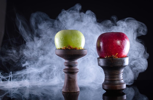 fruit hookah bowls with tobacco two apple and smoke on black background