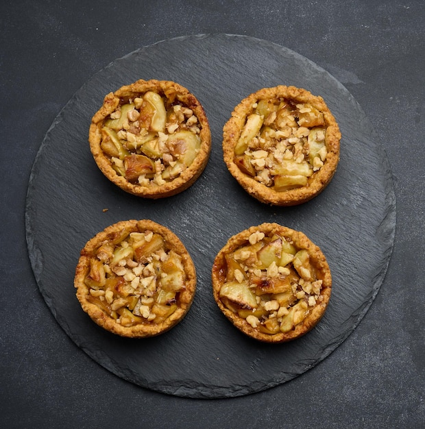 Fruit mini tart with apples on a black round graphite board top view