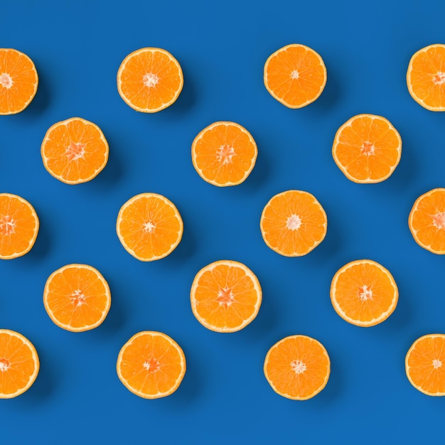 Fruit pattern of fresh orange tangerine or mandarin on blue background Flat lay top view Pop art design creative summer concept Citrus in minimal style