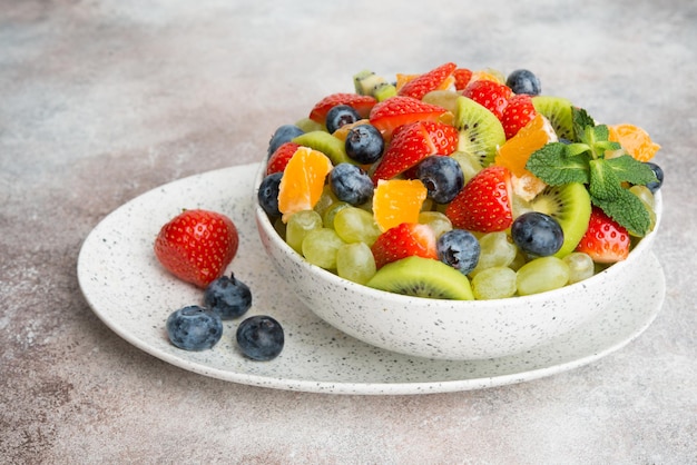 Fruit salad of blueberries, strawberries, grapes and kiwi in a plate, a copy of space