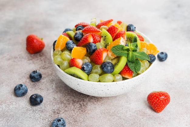 Fruit salad of blueberries, strawberries, grapes and kiwi in a plate, selective focus