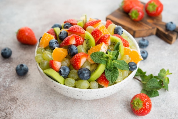 Fruit salad of blueberries, strawberries, grapes and kiwi in a plate, selective focus