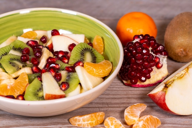 Fruit salad in a ceramic bowl and various fruits on a wooden table Superfood vegetarian food heal