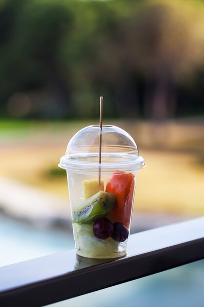 Fruit salad in a plastic cup against the of nature