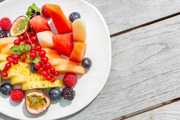 Fruit salad, simple wooden background and fresh fruits.