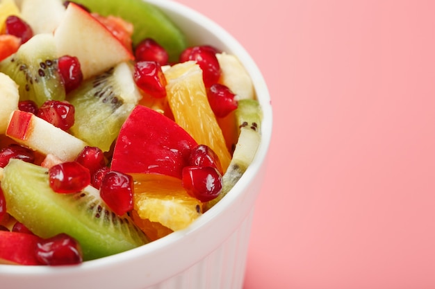 Fruit salad in a white cup on pink