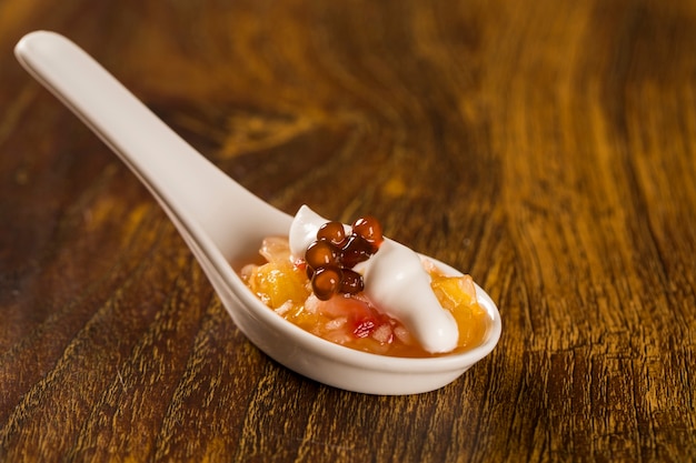 Fruit salad with meringue and coffee sago in a spoon