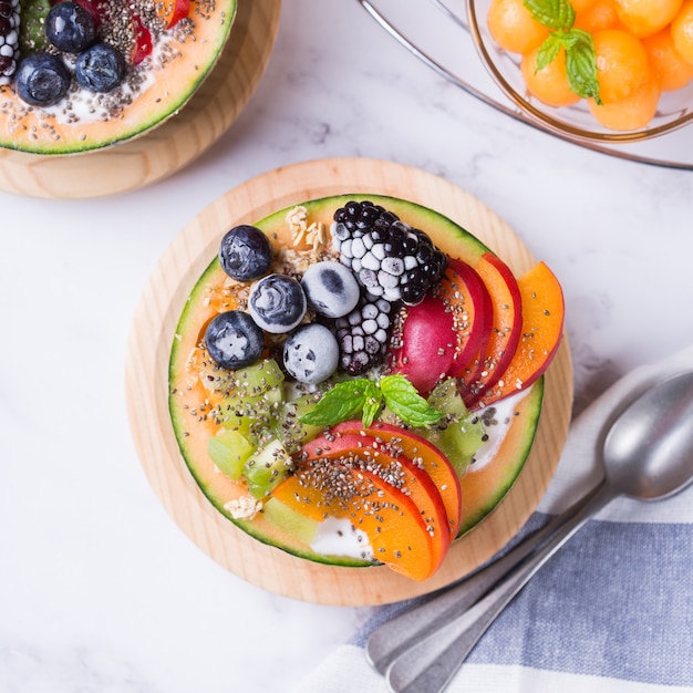 Fruit salad with yogurt in carved melon cantaloupe bowl