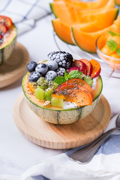 Fruit salad with yogurt in carved melon cantaloupe bowl