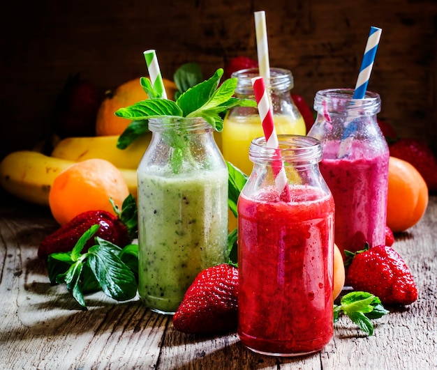 Fruit smoothies with colored straws in glass bottles selective focus