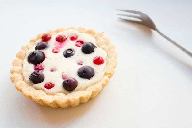 A fruit tart with a fork on a table