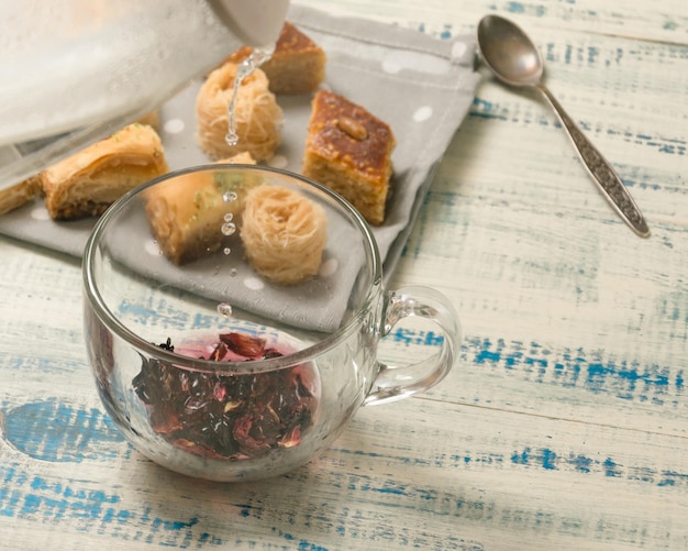 Fruit tea cooking Pouring boiling water in a cup on the background of oriental sweets