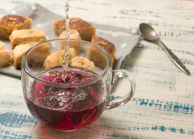 Fruit tea cooking Pouring boiling water in a cup on the background of oriental sweets