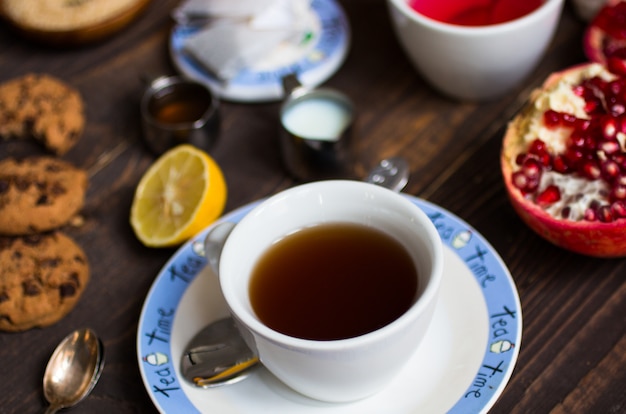 Fruit tea with lemon, milk,honey,orange, pomegranate, on a wooden surface