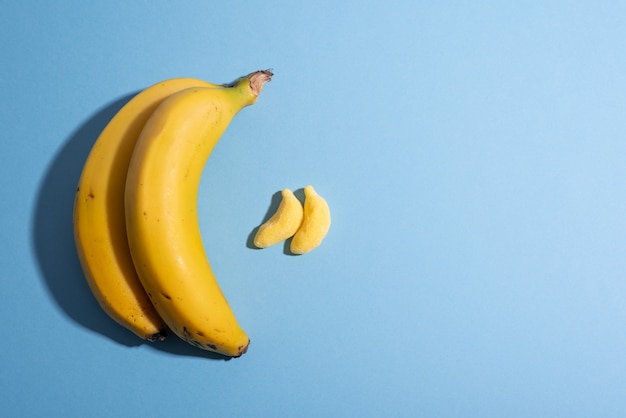 Fruit versus candy concept with bananas on plain blue