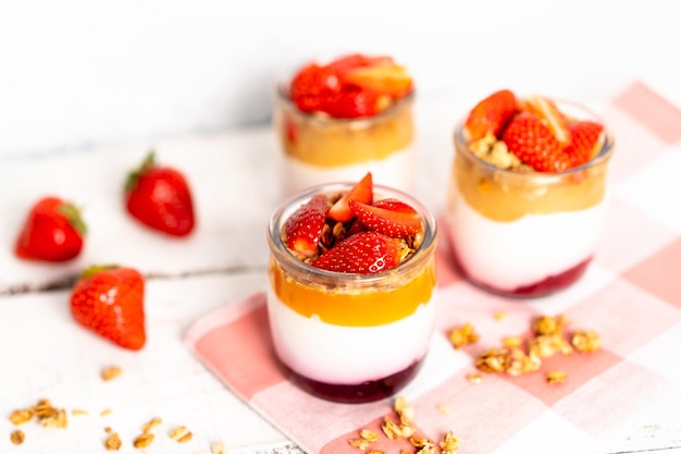 Fruit yogurt berry with muesli and fresh strawberries on a white wooden background