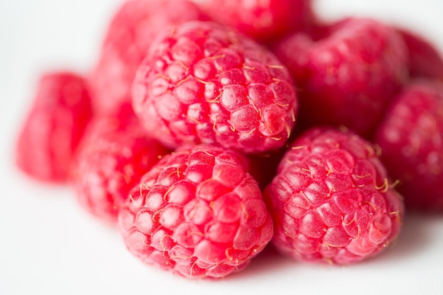 fruits, berries, diet, eco food and objects concept - juicy fresh ripe red raspberries on white