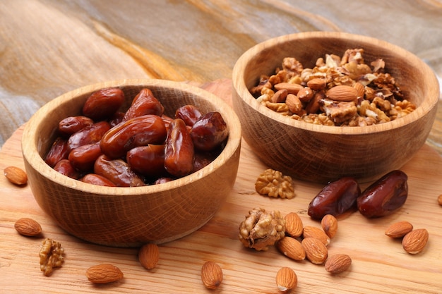 Fruits dates and nuts  in wooden bowl closeup on  table