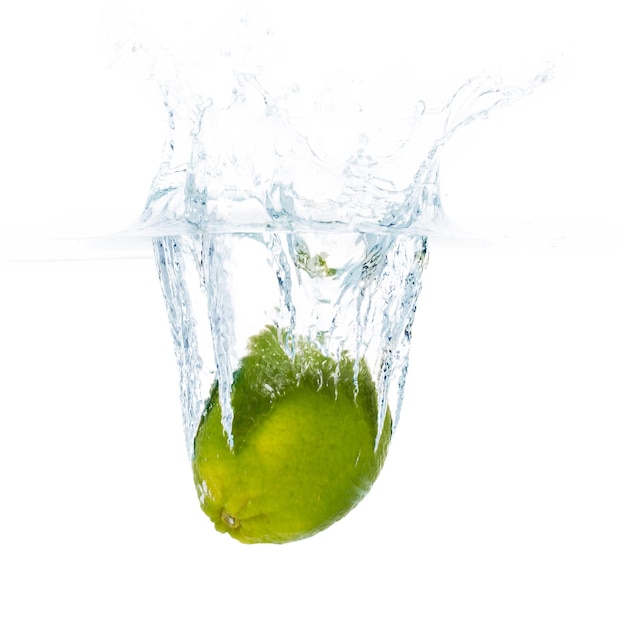 fruits, food and healthy eating concept - close up of fresh lime falling or dipping in water with splash over white background