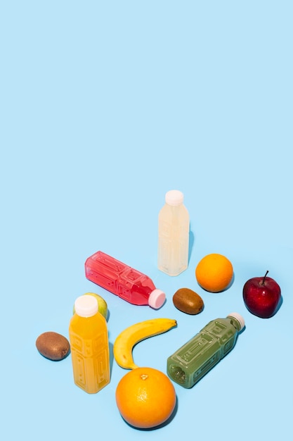 Photo fruits, juices detox in plastic bottles on a blue background.