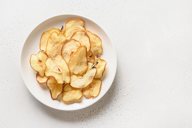 Fruits pear chips and water in sunny hard shadow on a white tiled background Vegan dessert sugar free View from above Copy space