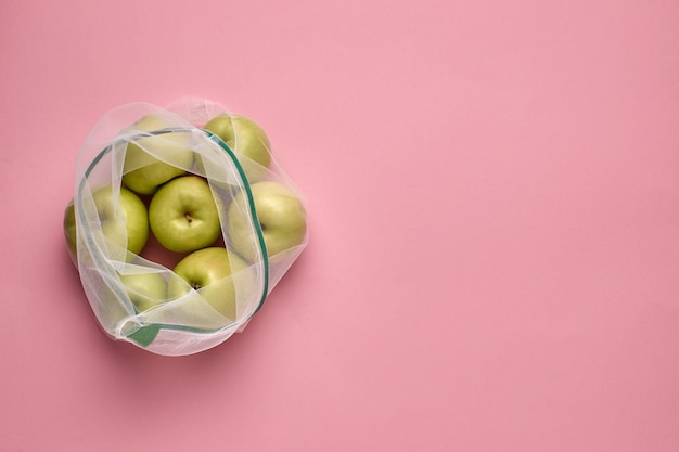 Fruits in reusable eco-friendly bags on pink background. Zero waste. Copy Space