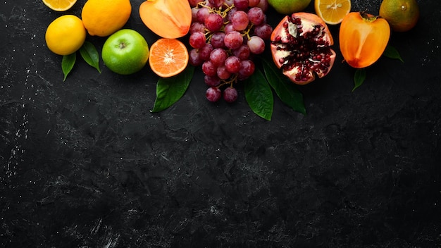 Fruits Seasonal and tropical fruits on a black stone background Food background Top view Free space for your text