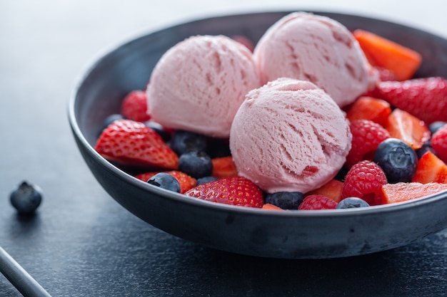 Fruity strawberry Ice cream scoops served on plate with fruits. Closeup