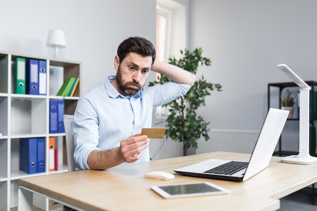 Frustrated and angry man in the office trying to make a purchase in an online store a businessman with a bank credit card angry got a banking error