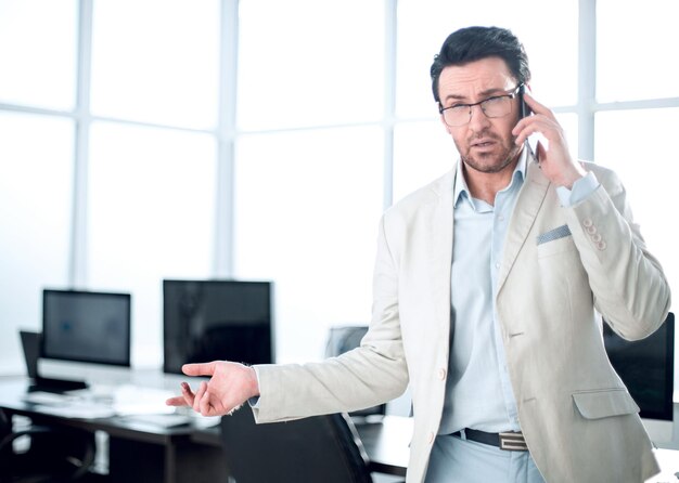 Frustrated businessman talking on mobile in an empty officephoto with copy space