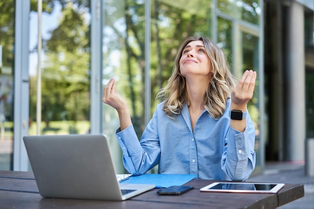 Frustrated businesswoman sitting on street with laptop and looking upset disappointed concept of fai