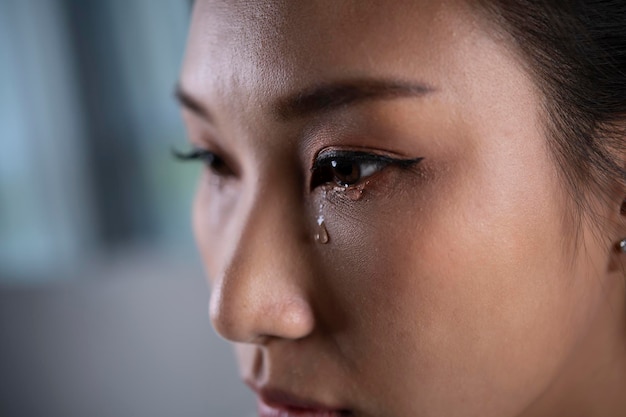 Frustrated and depressed young Asian woman is crying tears coming from her eyes sad Asian female feel down thinking about problems