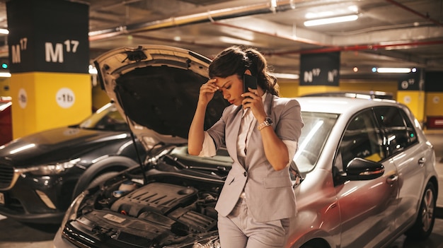 Frustrated and distressed woman has a car failure at public place in underground garage.