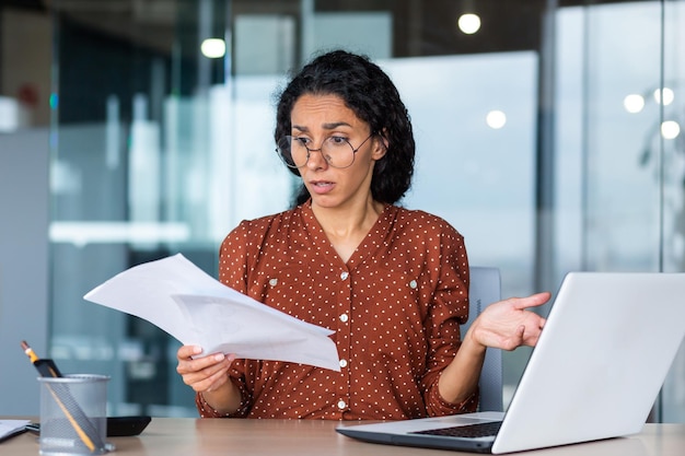 Frustrated and sad business woman holding financial report in hands hispanic woman sad working in