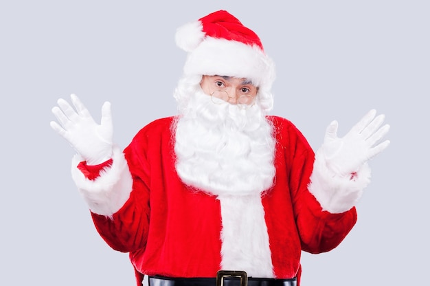 Frustrated Santa. Frustrated Santa Claus looking at camera and gesturing while standing against grey background