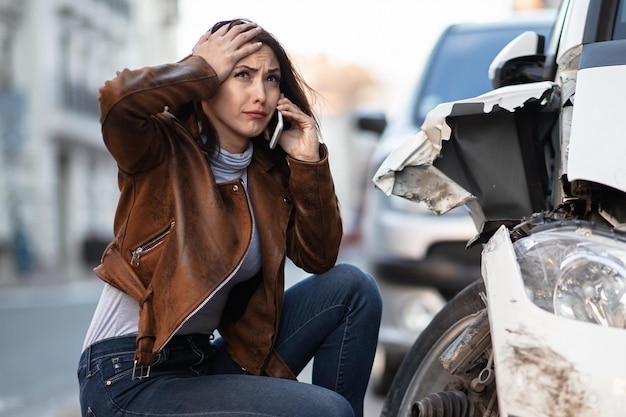 Frustrated woman calling for road assistance after the car accident