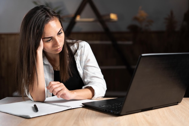 Frustrated woman working at home remotely online on a laptop is experiencing stress and burnout Millennial is an unmotivated employee sitting at a desk in her home office