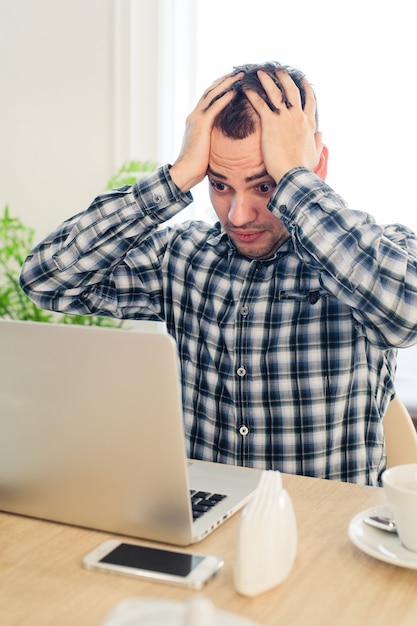 Frustrated young man working on a laptop