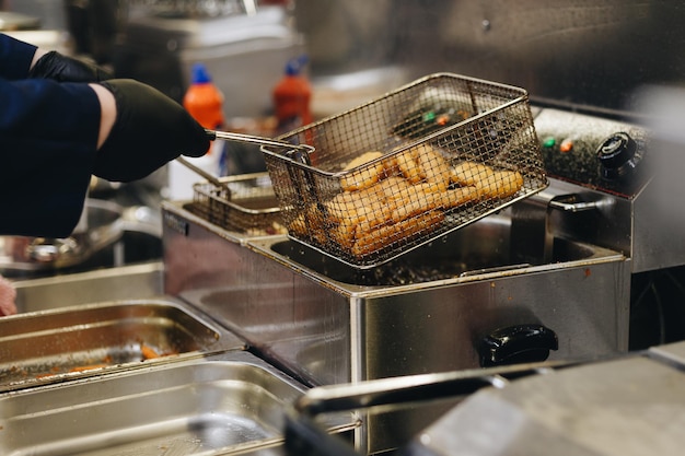 Frying chicken nuggets in deep fryer Restaurant meal preparation