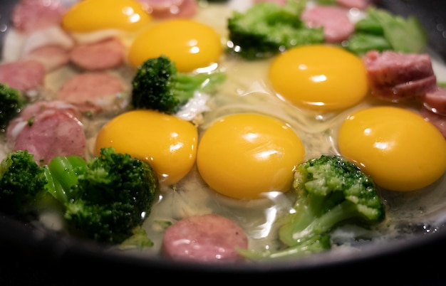 Frying eggs. Close up view of the fried eggs on frying pan. Fried eggs with veggies and meat on pan