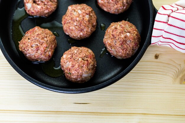 Frying large homemade Italian meatballs on a midium frying pan for dinner.