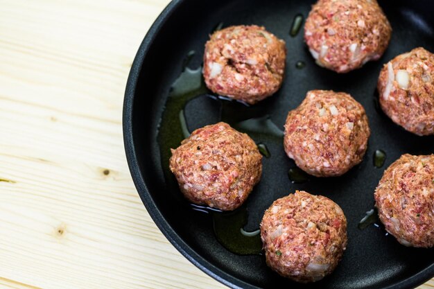 Frying large homemade Italian meatballs on a midium frying pan for dinner.