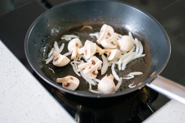 Frying onions and mushrooms in a pan on an induction stove