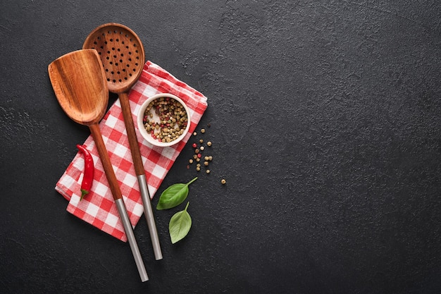 Frying pan white black empty plate basil leaves and spices on dark stone background Abstract food background Top view of dark rustic kitchen table with wooden cooking utensils frame Mock up