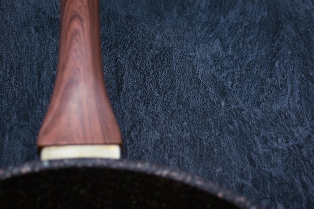 A frying pan with a wooden handle on a ceramic chair Closeup Selective focus on the table Copy Space